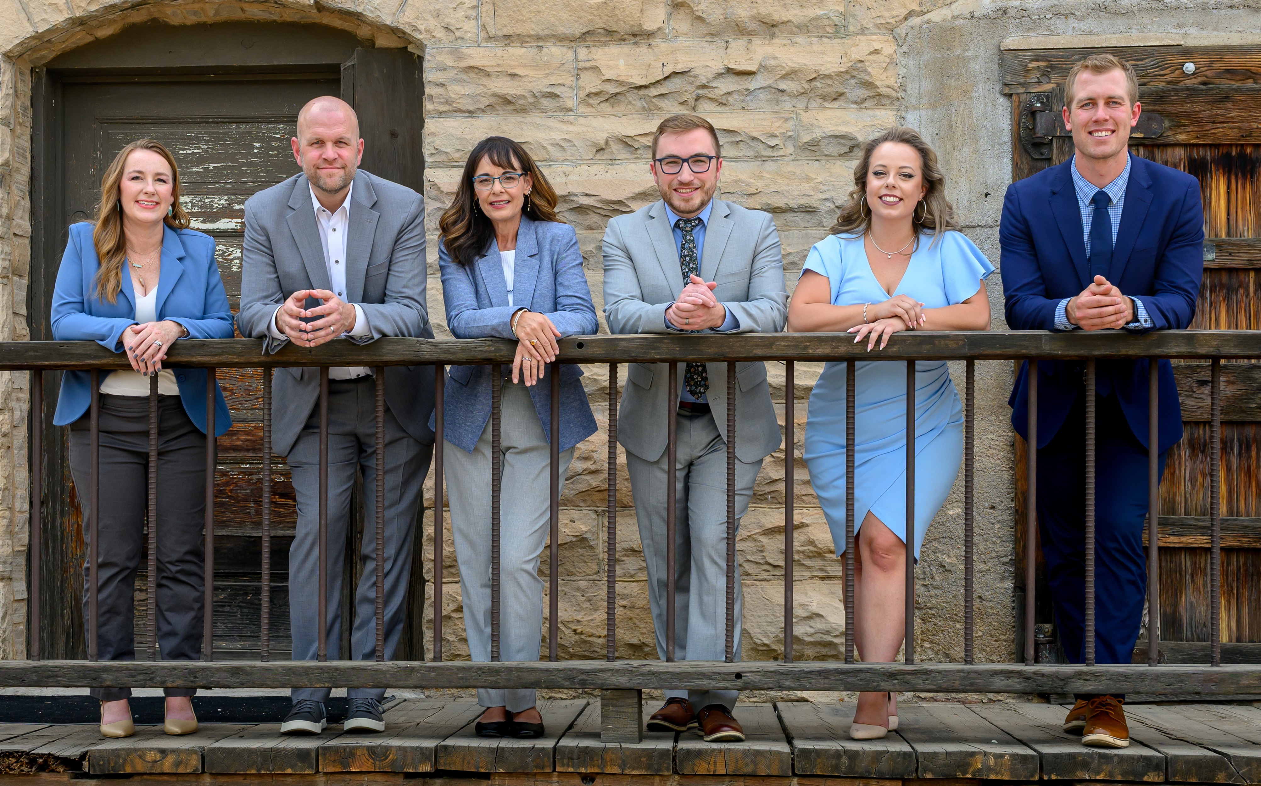 3 women and 4 men in business clothing with mountain backdrop smiling at the camera