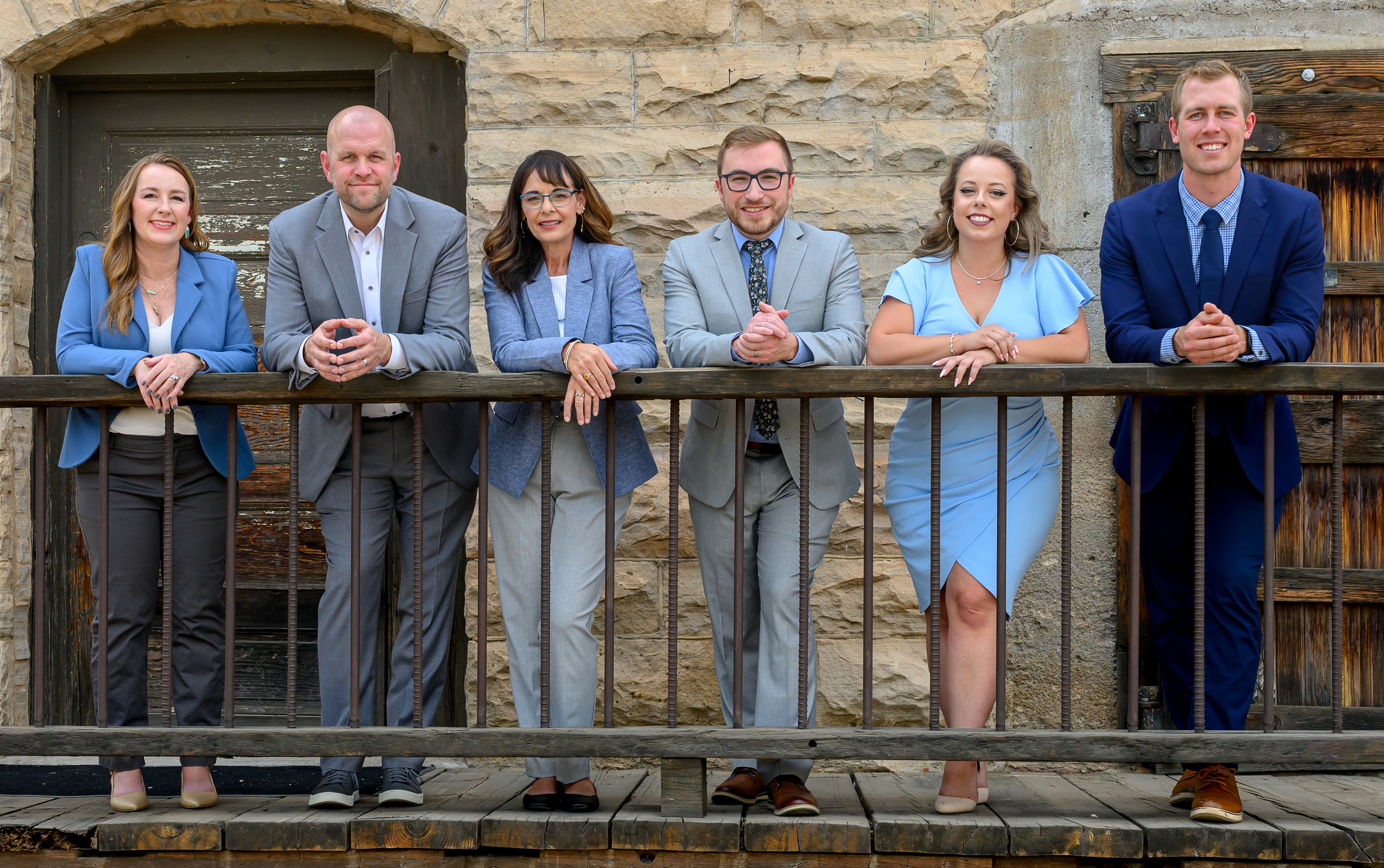 3 women and 4 men in business clothing with mountain backdrop smiling at the camera