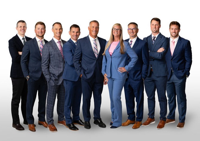 Team photo of eight men and one woman in professional attire
