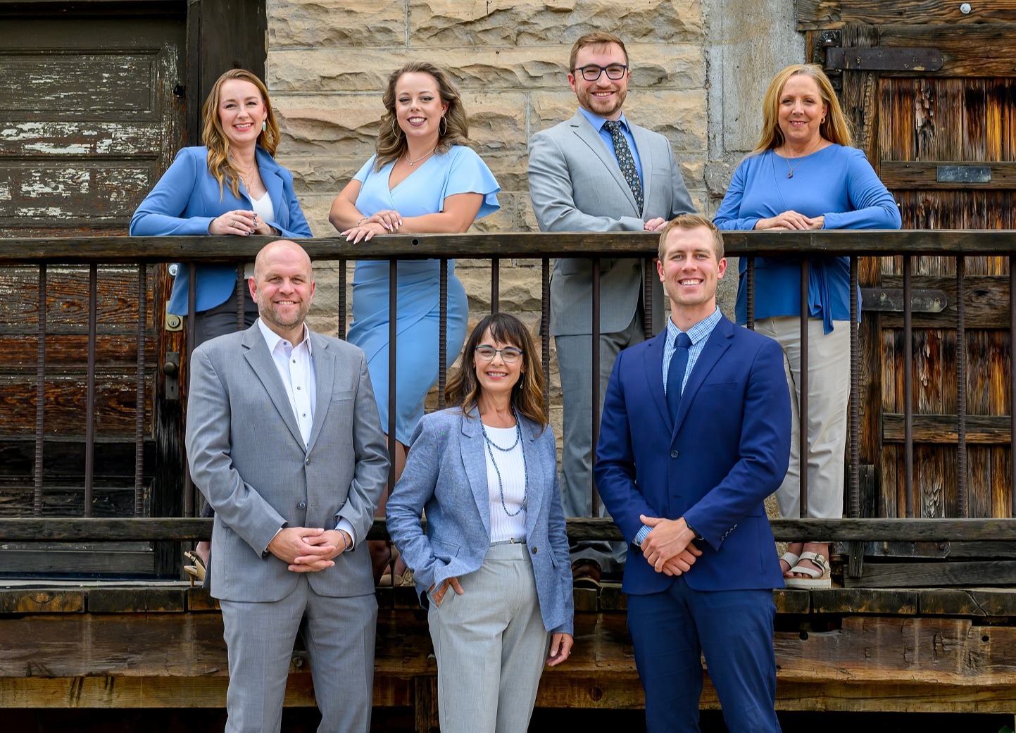 3 women and 4 men in business clothing with mountain backdrop smiling at the camera